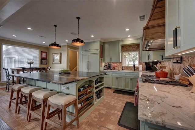 kitchen with paneled built in refrigerator, a center island, hanging light fixtures, and dark stone counters