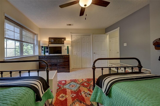 bedroom with ceiling fan, carpet, and a textured ceiling