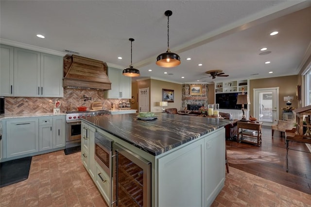 kitchen with stainless steel stove, wine cooler, ceiling fan, a kitchen island, and custom range hood