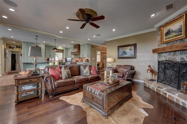 living room featuring hardwood / wood-style floors, ceiling fan, ornamental molding, and a fireplace