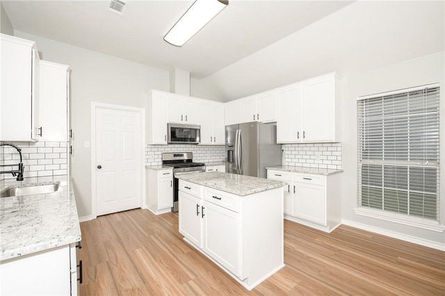 kitchen featuring decorative backsplash, white cabinetry, light hardwood / wood-style flooring, and stainless steel appliances