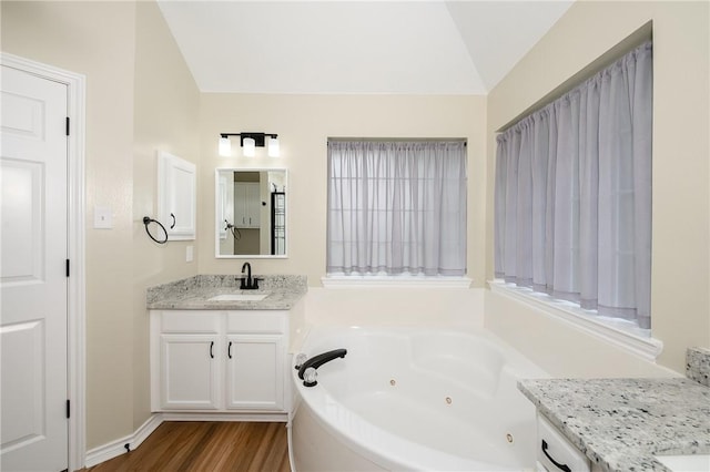 bathroom with hardwood / wood-style flooring, vanity, lofted ceiling, and a tub to relax in