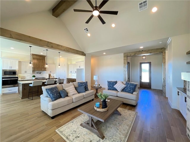 living room with ceiling fan, beamed ceiling, and high vaulted ceiling