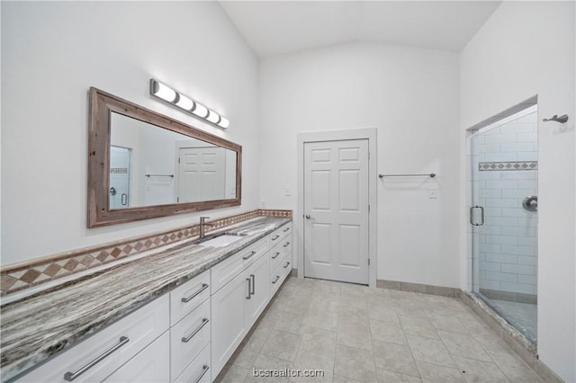 bathroom featuring tile patterned floors, vanity, a shower with shower door, and lofted ceiling