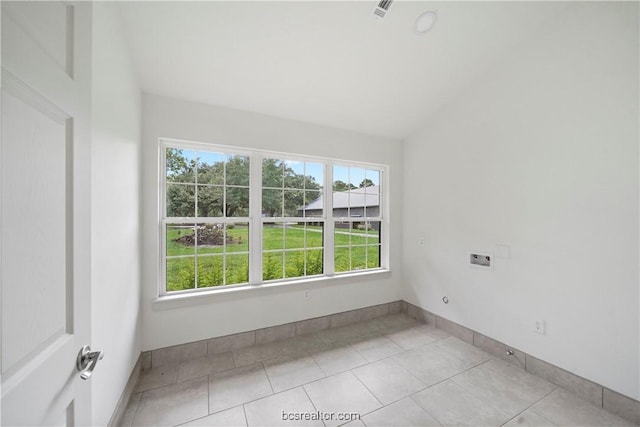 tiled empty room featuring lofted ceiling