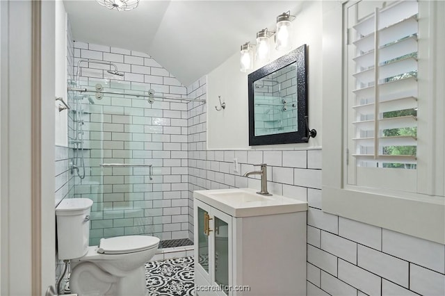 bathroom with tile patterned flooring, vaulted ceiling, toilet, tiled shower, and tile walls