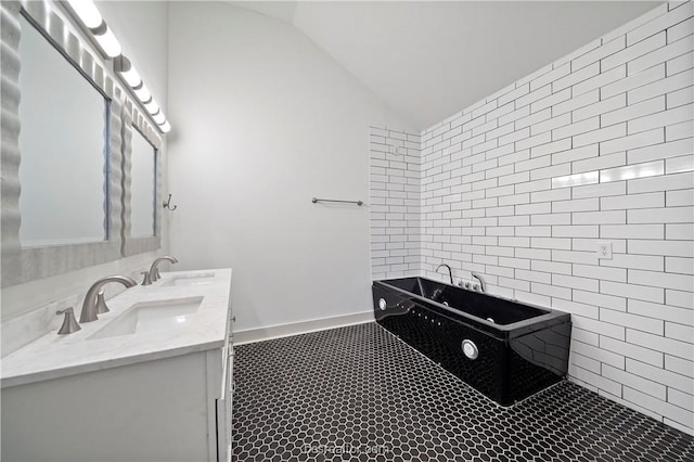 bathroom featuring tile patterned flooring, vanity, a tub to relax in, and vaulted ceiling