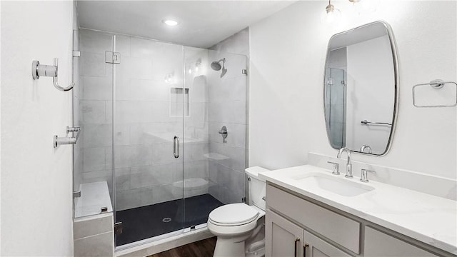 bathroom featuring vanity, toilet, wood finished floors, and a stall shower