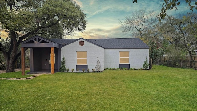 view of front of property with brick siding, a lawn, and fence