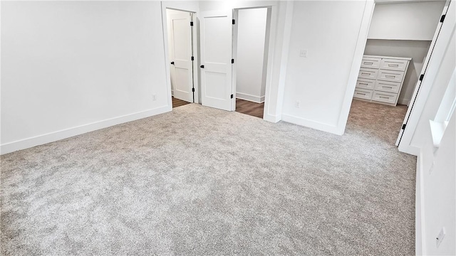 unfurnished bedroom with a closet, baseboards, a walk in closet, and carpet