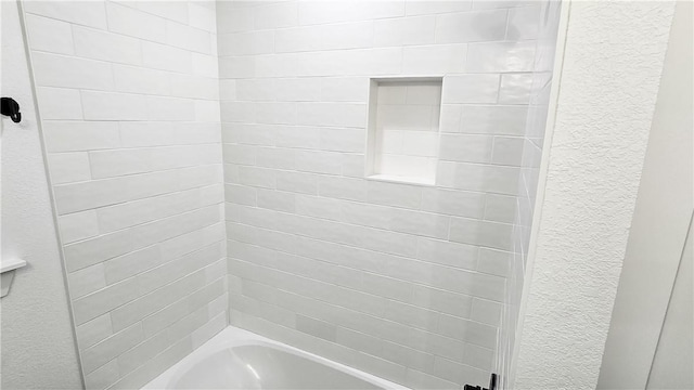 bathroom featuring shower / tub combination and a textured wall