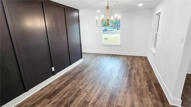 unfurnished dining area with a notable chandelier, recessed lighting, dark wood-type flooring, and baseboards