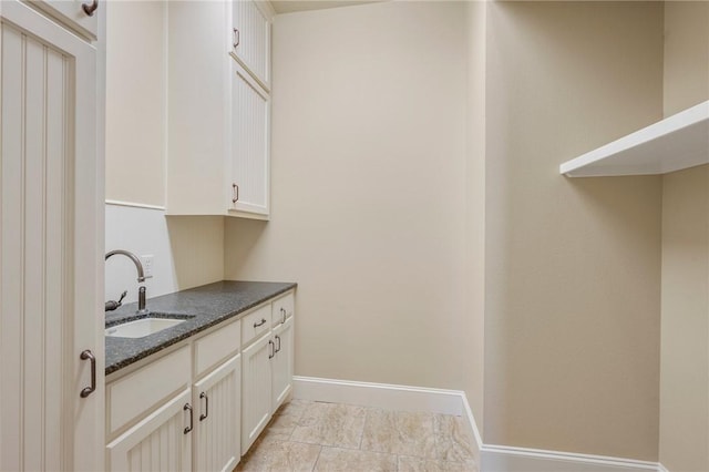 interior space with baseboards, a sink, and light tile patterned flooring