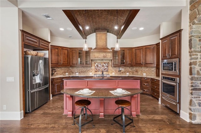 kitchen with appliances with stainless steel finishes, brick ceiling, premium range hood, and dark wood-type flooring