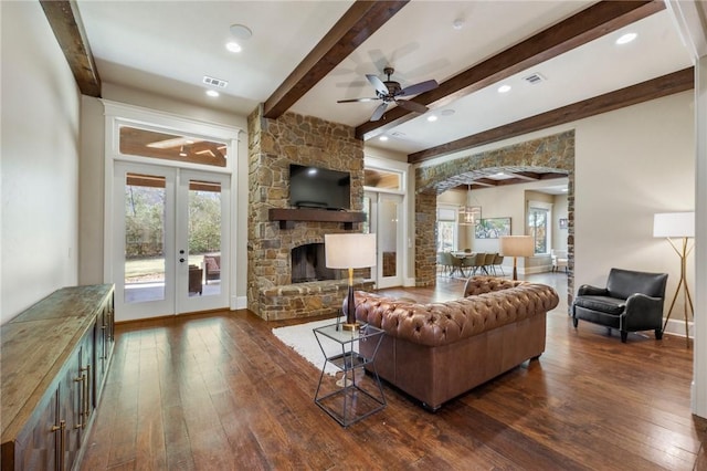 living room with arched walkways, french doors, dark wood-type flooring, and visible vents