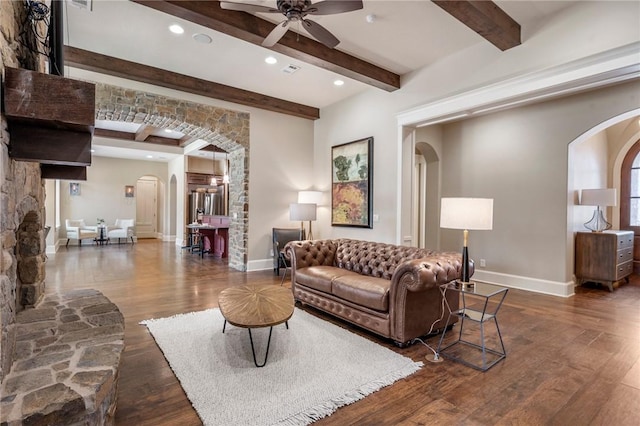 living room with baseboards, arched walkways, ceiling fan, wood finished floors, and beam ceiling