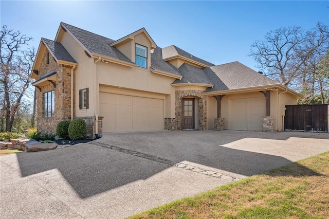 view of front of home featuring stone siding, a shingled roof, an attached garage, and stucco siding