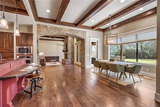 dining space featuring arched walkways, beam ceiling, dark wood finished floors, and baseboards