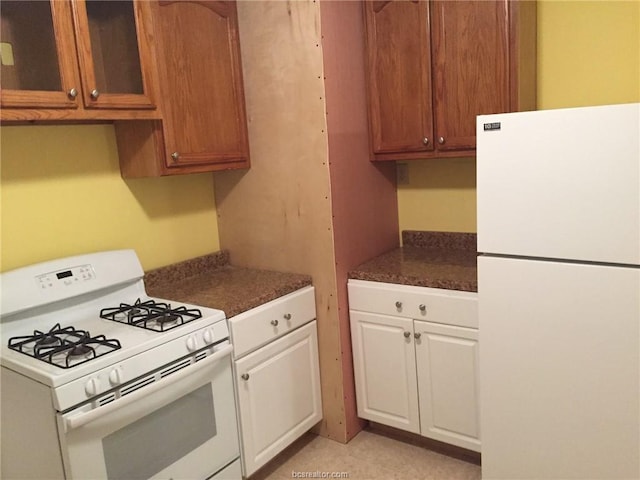 kitchen with glass insert cabinets, white appliances, white cabinetry, and brown cabinetry