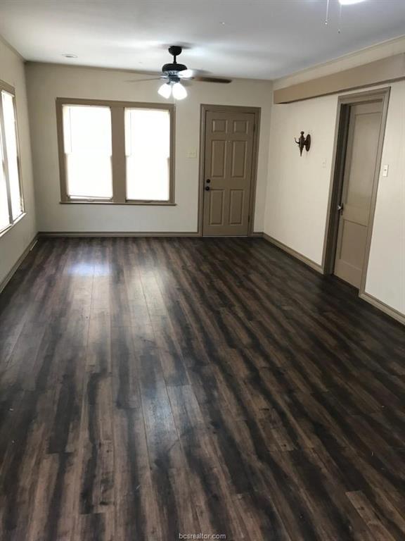 unfurnished living room featuring dark wood-style floors, baseboards, and a ceiling fan