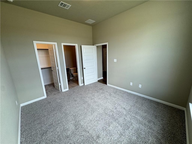 unfurnished bedroom with carpet, a walk in closet, ensuite bathroom, and a closet