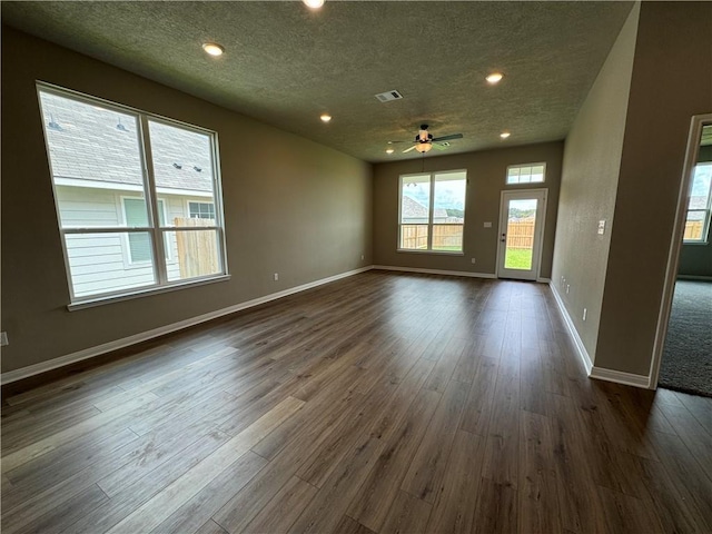 spare room with a textured ceiling, ceiling fan, and dark hardwood / wood-style floors