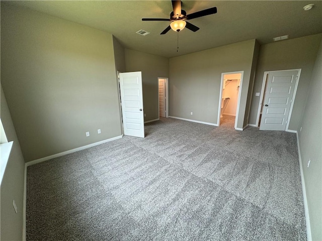 unfurnished bedroom featuring carpet floors, a closet, ensuite bath, and ceiling fan