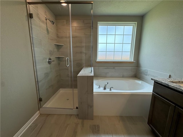 bathroom featuring vanity, wood-type flooring, a textured ceiling, and shower with separate bathtub