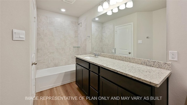 bathroom featuring tiled shower / bath combo, hardwood / wood-style flooring, and vanity