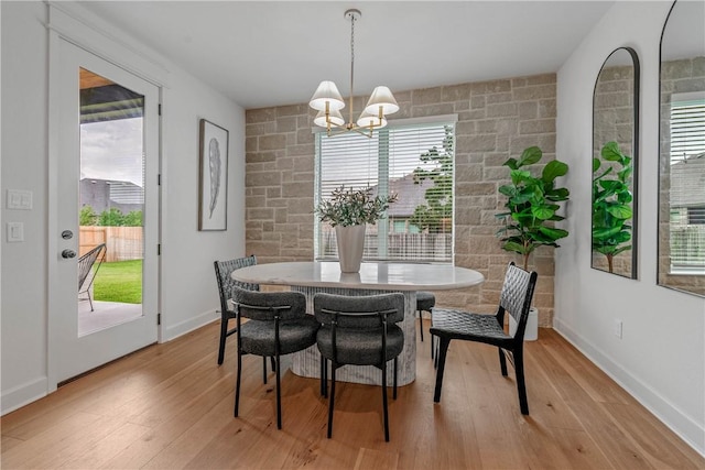 dining area with plenty of natural light, a notable chandelier, and light wood-type flooring