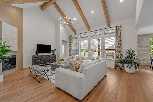 living room with high vaulted ceiling, light hardwood / wood-style flooring, beamed ceiling, a notable chandelier, and a large fireplace