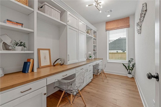 home office with light wood-type flooring and built in desk