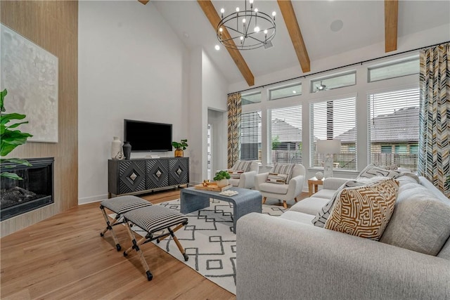 living room with a large fireplace, high vaulted ceiling, beamed ceiling, a notable chandelier, and wood-type flooring