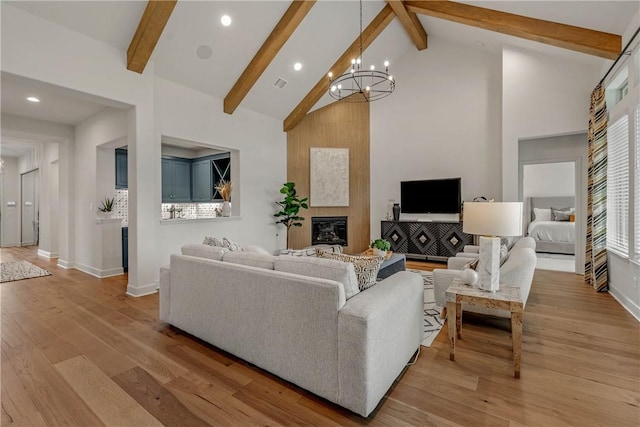 living room with beam ceiling, an inviting chandelier, high vaulted ceiling, and light hardwood / wood-style flooring