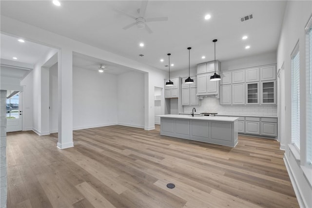 5020 Toscana Loop, Bryan, TX 77802 - kitchen with a sink, a kitchen island with sink, light countertops, a ceiling fan, and backsplash