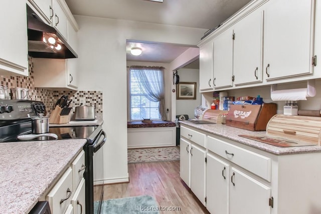 kitchen with tasteful backsplash, white cabinets, stainless steel stove, and light wood-type flooring