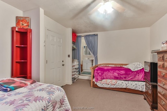 bedroom featuring light colored carpet, ensuite bath, and ceiling fan