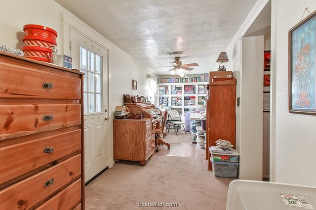 interior space with a textured ceiling, light colored carpet, and ceiling fan