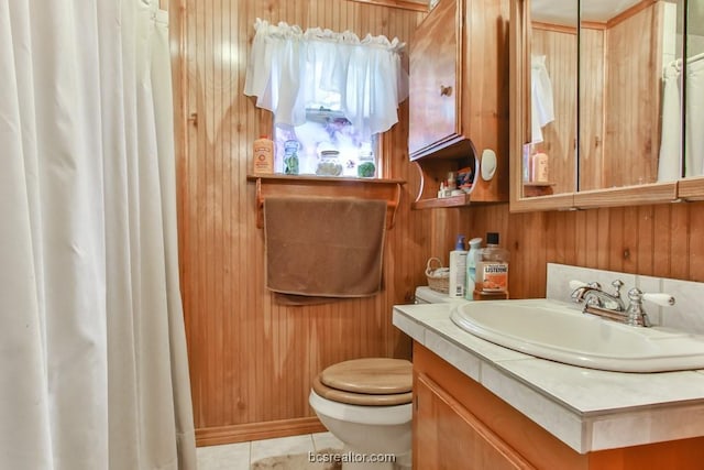 bathroom with tile patterned floors, vanity, toilet, and wood walls