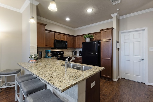 kitchen with pendant lighting, black appliances, sink, dark hardwood / wood-style floors, and kitchen peninsula