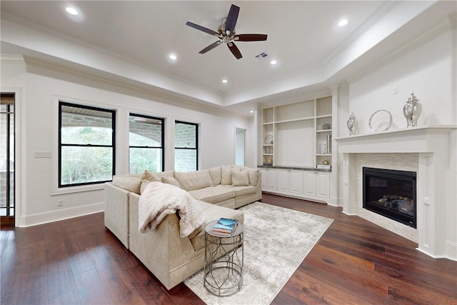 living room featuring a raised ceiling, ceiling fan, dark wood-type flooring, and a premium fireplace