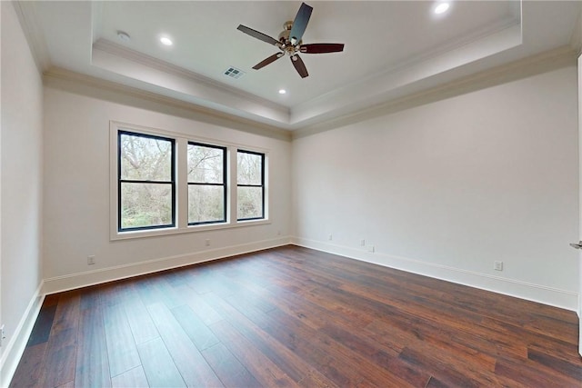 empty room featuring dark hardwood / wood-style floors, a raised ceiling, ceiling fan, and ornamental molding