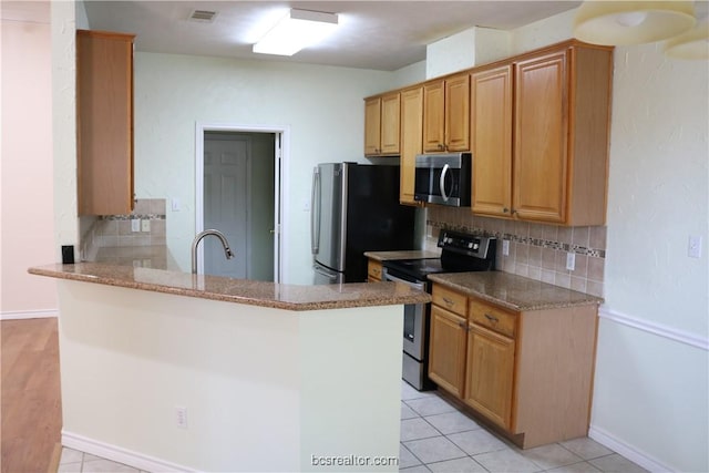 kitchen featuring decorative backsplash, stainless steel appliances, and kitchen peninsula