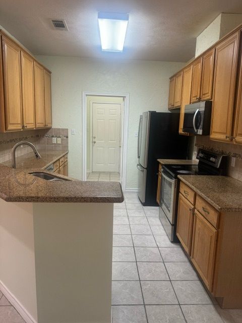 kitchen featuring kitchen peninsula, appliances with stainless steel finishes, and decorative backsplash