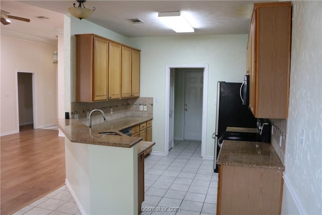 kitchen featuring stone counters, sink, backsplash, kitchen peninsula, and light wood-type flooring