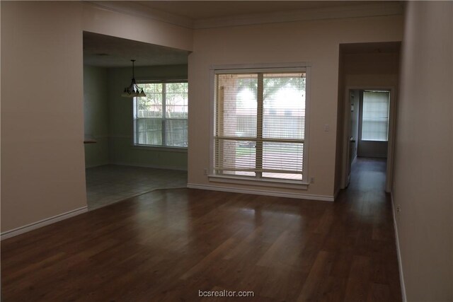 unfurnished room with dark hardwood / wood-style flooring, an inviting chandelier, and crown molding