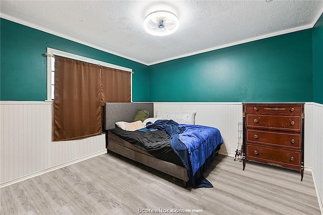 bedroom featuring a textured ceiling, light hardwood / wood-style flooring, and crown molding