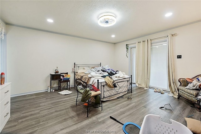 bedroom with hardwood / wood-style floors, ornamental molding, and a textured ceiling