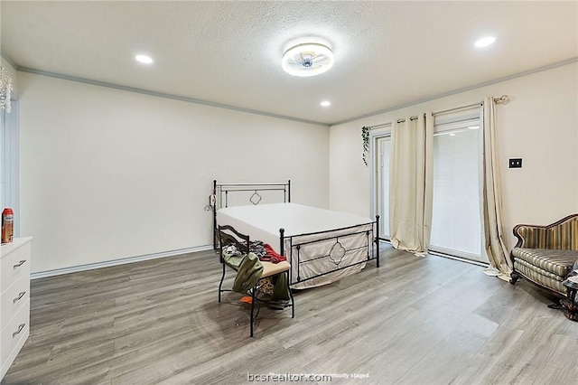 bedroom with light wood-type flooring, a textured ceiling, and ornamental molding