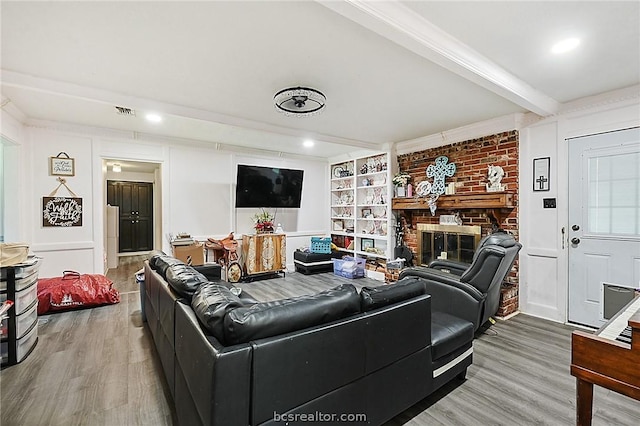 living room featuring beamed ceiling, wood-type flooring, and a fireplace